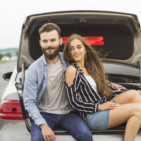 smiling-couple-sitting-inside-car-open-trunk