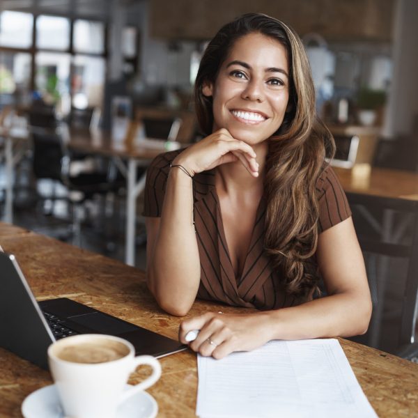 Successful ambitious female entrepreneur interviewing you during meeting seek employee look pleasantly camera smiling friendly sit near laptop read applicant cv, drinking coffee.